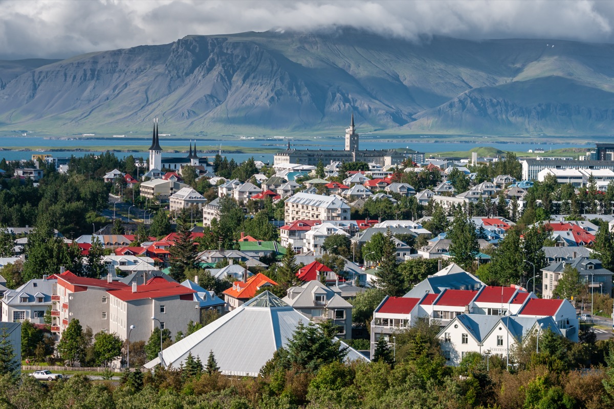 Stadtpanorama von Reykjavík mit bunten Hausdächern, Kirchturm und den Bergen im Hintergrund